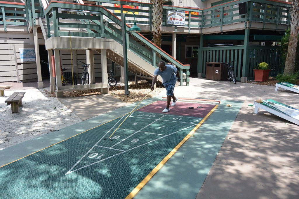 A smiling man plays shuffleboard at Disney's Hilton Head Island Resort